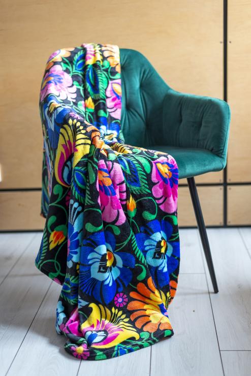 black blanket with folk lowicz flowers hung over a green armchair