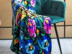 black blanket with folk lowicz flowers hung over a green armchair