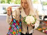 woman puts cauliflower in a folk cotton black bag